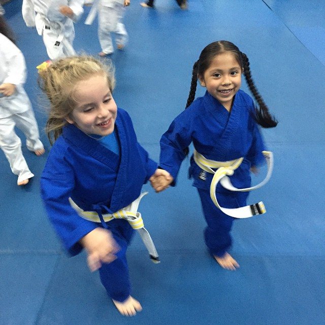 Two young students in blue uniforms smiling on the mats